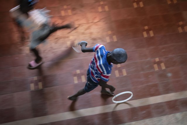 A youth rolls a hoop in the National Theater where families displaced by gang violence are taking shelter in Port-au-Prince, Haiti, May 9, 2024. (Photo by Ramon Espinosa/AP Photo)