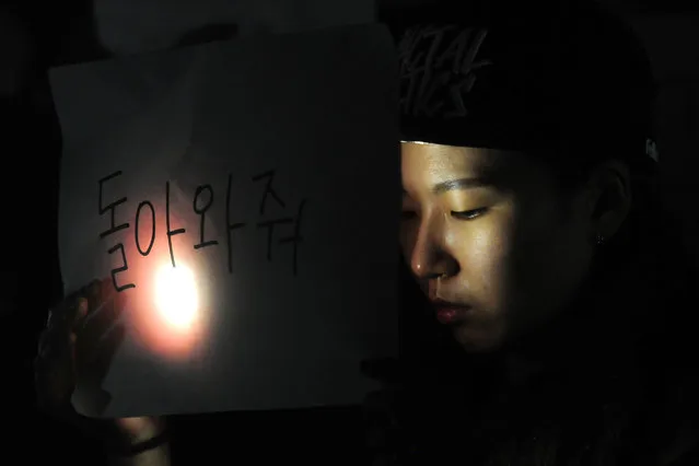 Family and schoolmates of missing passengers of the Sewol ferry accident hold candles during a vigil at Danwon High School in Ansan, South Korea, 17 April 2014. Nearly 300 people were still missing and at least nine confirmed dead after a passenger ferry carrying hundreds of teenagers sank off the southern coast of South Korea on 16 April. (Photo by Yang Ji-Woong/EPA)