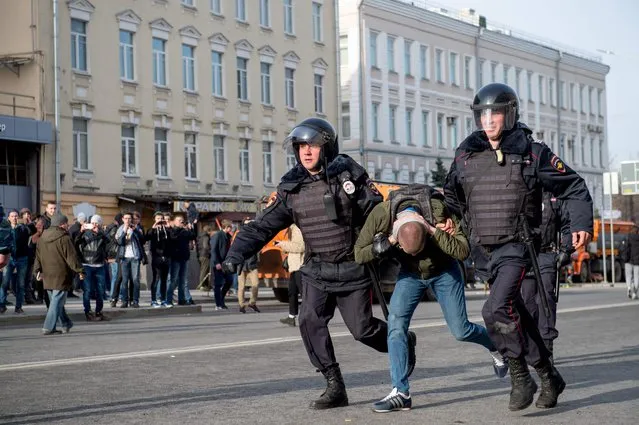 Riot police officers detain a protester during an unauthorised anti-corruption rally in central Moscow on March 26, 2017. Thousands of Russians demonstrated across the country on March 26 to protest at corruption, defying bans on rallies which were called by prominent Kremlin critic Alexei Navalny – who was arrested along with scores of others. Navalny called for the protests after publishing a detailed report this month accusing Prime Minister Dmitry Medvedev of controlling a property empire through a shadowy network of non-profit organisations. (Photo by Alexander Utkin/AFP Photo)