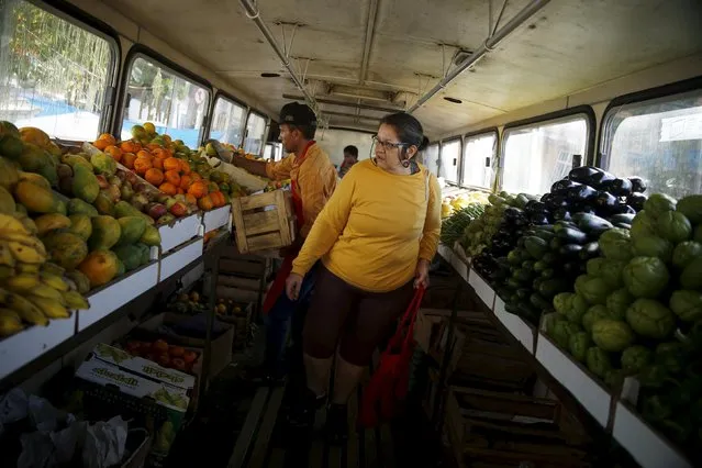 A woman looks for fruits to buy inside a bus called Sacolao in Santa Teresa neighborhood in Rio de Janeiro, Brazil, July 7, 2015. (Photo by Pilar Olivares/Reuters)