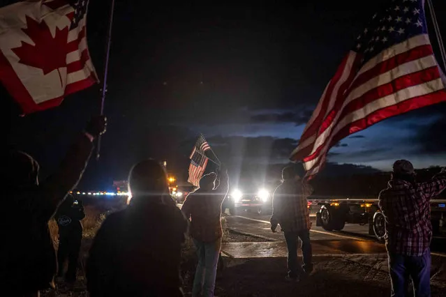 Supporters cheer on a trucker caravan as it pulls off the highway for the night while heading toward Washington D.C. to protest COVID-19 mandates on Wednesday, February 23, 2022, in Kingman, Az. (Photo by Nathan Howard/AP Photo)