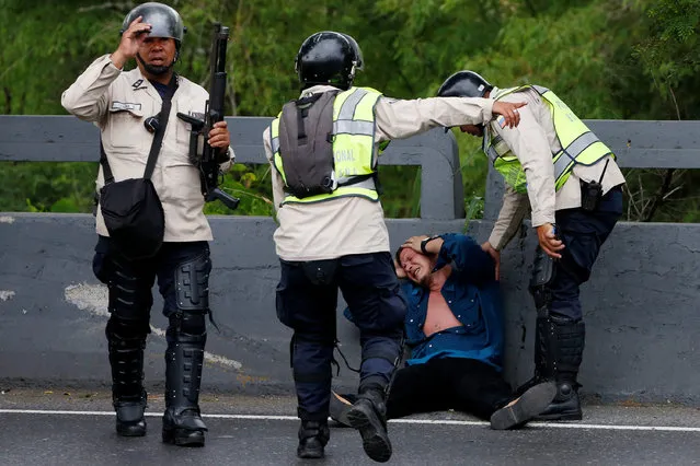 Riot policemen help an injured protester during a rally to demand a referendum to remove President Nicolas Maduro in Caracas, Venezuela, May 11, 2016. (Photo by Carlos Garcia Rawlins/Reuters)
