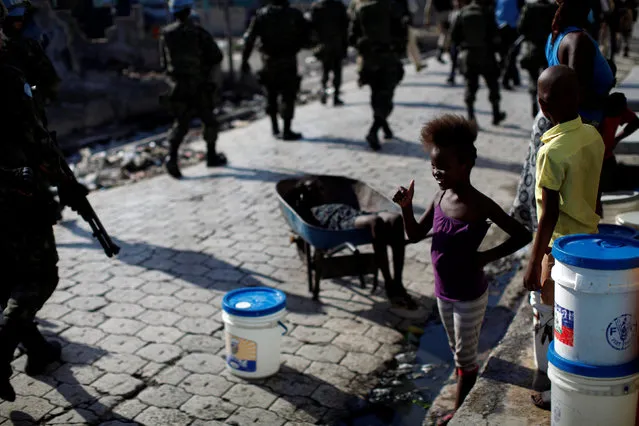 A girl greets U.N. peacekeepers, Haitian national police officers and members of UNPOL (United Nations Police) as they walk along a street during a patrol in Cite Soleil, Port-au-Prince, Haiti, March 3, 2017. (Photo by Andres Martinez Casares/Reuters)