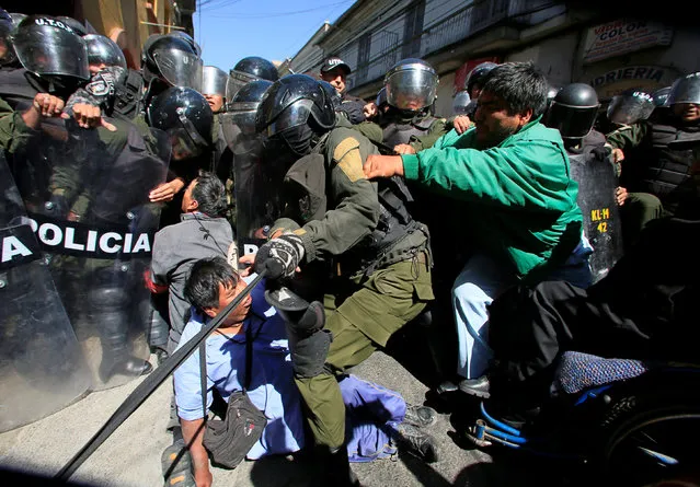 Demonstrators with physical disabilities try to break through a barricade by riot police during a protest calling on the government to provide a monthly subsidy rather than an annual one in La Paz, Bolivia, Bolivia, May 12, 2016. (Photo by David Mercado/Reuters)