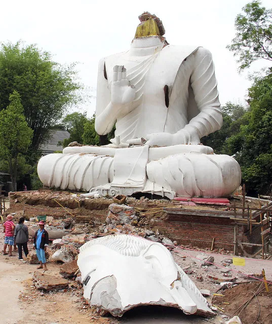 Thai villagers examine a damaged Buddha statue following an earthquake in Chiang Rai province, northern Thailand, Tuesday, May 6, 2014. Officials said Tuesday that one person was killed and several dozen were hurt in the earthquake that struck northern Thailand and Myanmar a day earlier, smashing windows, cracking walls and roads and damaging Buddhist temples. (Photo by Wichai Taprieu/AP Photo)