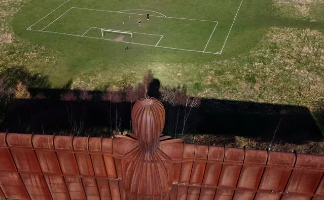 People play football on a pitch next to Antony Gormley’s Angel of the North in Gateshead, Britain, March 20, 2022. (Photo by Lee Smith/Reuters)