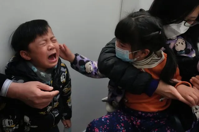 A boy cries after receiving a dose of China's Sinovac COVID-19 coronavirus vaccine at a community vaccination center in Hong Kong on Feb. 25, 2022. The fast-spreading omicron variant is overwhelming Hong Kong, prompting mass testing, quarantines, supermarket panic-buying and a shortage of hospital beds. Even the morgues are overflowing, forcing authorities to store bodies in refrigerated shipping containers. (Photo by Kin Cheung/AP Photo)