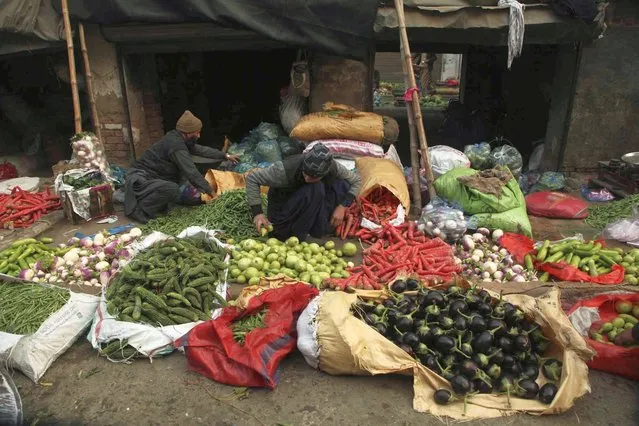A Pakistani vegetable seller waits for customers at a market in Peshawar, Pakistan, Wednesday, December 22, 2021. (Photo by Mohammad Sajjad/AP Photo)