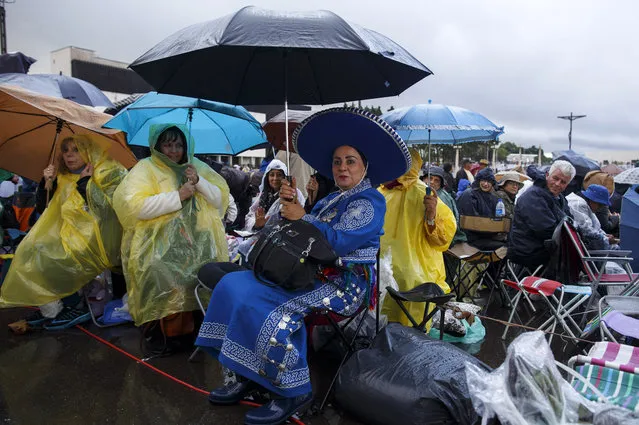 Worshippers sit with their umbrellas as they wait for the arrival of Pope Francis at the Sanctuary of Fatima on May 12, 2017 in Fatima, Portugal. Pope Francis will be attending the Sanctuary of Fatima, in Portugal, on May 12 and 13 to canonize two Portuguese shepherds, Jacinta and Francisco Marto, who are said to have witnessed the apparition of what they believed was the Virgin Mary, together with their aunt Lucia Santos, during the 100 anniversary. Thousands of pilgrims and worshippers from around the world are expected to gather at the centenary celebration. (Photo by Pablo Blazquez Dominguez/Getty Images)