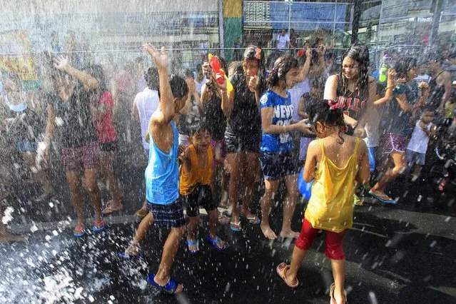 Water from the local firebrigade is showered on residents during traditional St. John the Baptist Feast Day celebrations in San Juan city, metro Manila June 24, 2014. Residents participate in an annual city-wide waterfest in honour of their patron Saint John the Baptist. (Photo by Romeo Ranoco/Reuters)