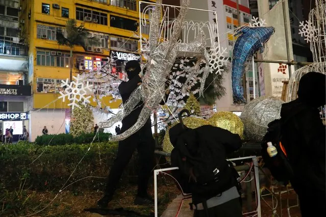 Anti-government protesters tear down Christmas and New Year's decorations during a demonstration on New Year's Eve outside Mong Kok police station in Hong Kong, December 31, 2019. (Photo by Tyrone Siu/Reuters)