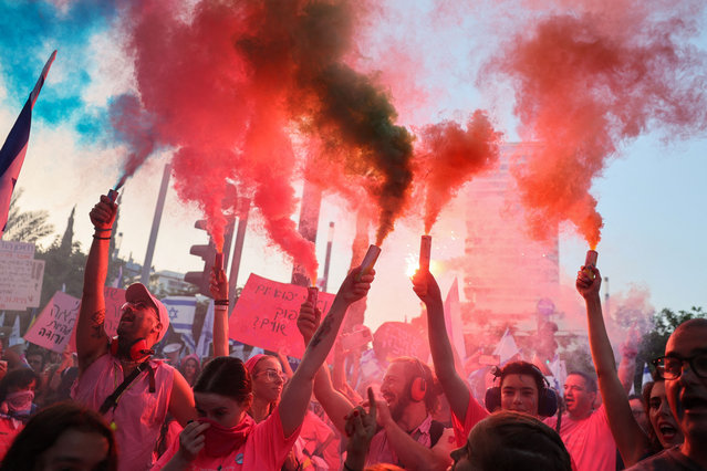 Demonstrators use flares during a rally protesting the Israeli government's judicial overhaul bill in Tel Aviv on June 10, 2023. (Photo by Jack Guez/AFP Photo)