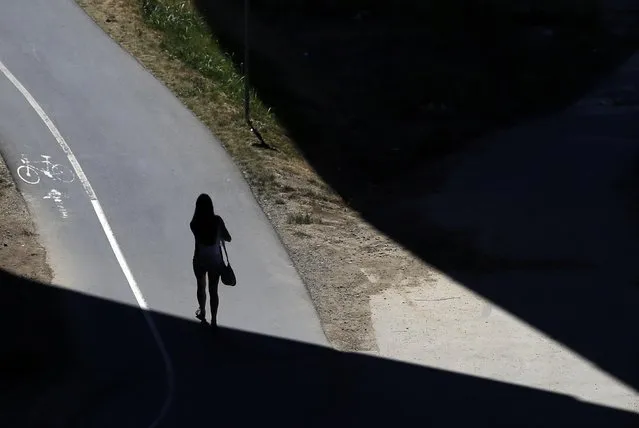 A girl walks through a shadow under the Ada bridge in Belgrade, Serbia, Tuesday, July 21, 2015. (Photo by Darko Vojinovic/AP Photo)