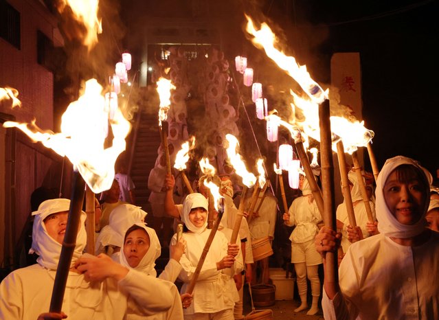 Volunteers in the white-clad of “Ama” female free divers, who harvest sea life from the ocean, hold torches as they prepare to swim into the sea at Shirahama Ama matsuri in Minamiboso, Chiba Prefecture, Japan on July 20, 2024. (Photo by Kim Kyung-Hoon/Reuters)