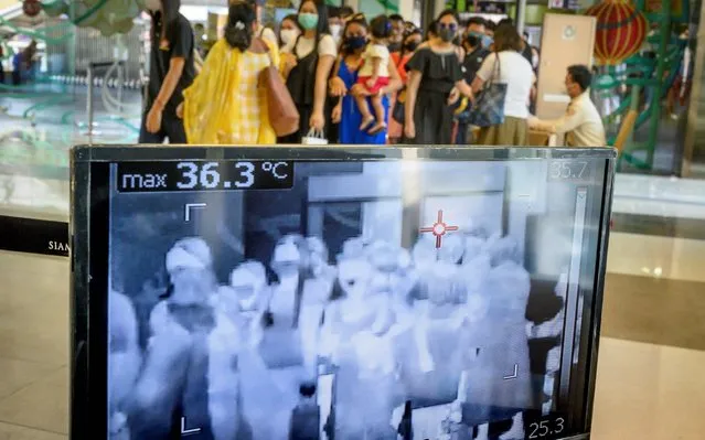 People with protective face masks pass in front of a thermal scanner as they enter a shopping mall in Bangkok on January 29, 2020. Thailand has detected 14 cases so far of the novel coronavirus, a virus similar to the SARS pathogen, an outbreak which began in the Chinese city of Wuhan. (Photo by Mladen Antonov/AFP Photo)