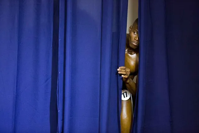 In this July 23, 2017 photo, a Haitian bodybuilder peers from behind the curtain to watch his competitors perform at the Haiti Bodybuilding Classic, an event with Haitian and Dominican Republican athletes, in Port-au-Prince, Haiti. It was the first such showdown between the neighboring countries whose relations are often tense. (Photo by Dieu Nalio Chery/AP Photo)