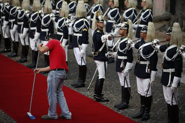A man sweeps the red carpet in front of an honor guard in Lisbon, Portugal. (Photo by Rafael Marchante/Reuters)