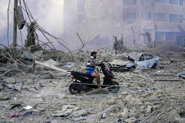 A man rides his scooter as he drives on the debris of destroyed buildings that were hit by Israeli airstrikes in Dahiyeh, Beirut, Lebanon, Sunday, October 6, 2024. (Photo by Hussein Malla/AP Photo)