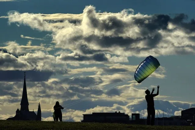 Nick Gumlaw, of Portland, Maine, right, releases a stunt kite controlled by Amanda Hutter, of Scarborough, Maine, as they take advantage of gusty winds, Tuesday, May, 17, 2022, in South Portland, Maine. (Photo by Robert F. Bukaty/AP Photo)