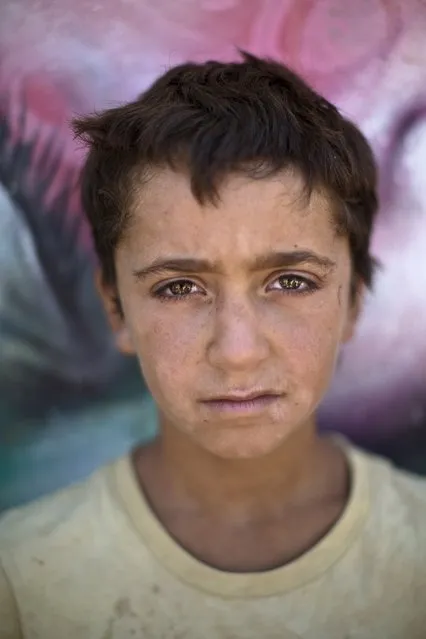 In this Tuesday, July 29, 2014 photo, Syrian refugee Fouad, 14, poses for a picture at Zaatari refugee camp, near the Syrian border, in Mafraq, Jordan. UNICEF estimates more than 10,000 children have died in the violence in Syria. Others suffer from emotional problems after experiencing the war. (Photo by Muhammed Muheisen/AP Photo)