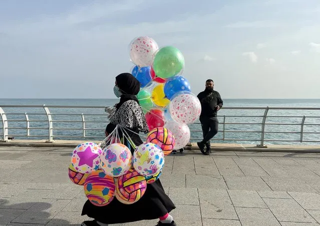A woman carries balloons for sale as she walks along a seaside promenade, during the Muslim holiday of Eid al-Fitr, in Beirut, Lebanon on May 2, 2022. (Photo by Yara Abi Nader/Reuters)
