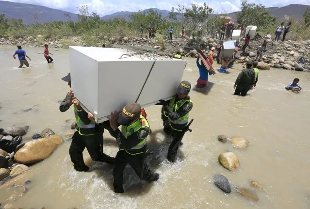 Colombian policemen carry items belonging to people arriving in Colombia while crossing the Tachira river border with Venezuela, near Villa del Rosario village August 25, 2015. (Photo by Jose Miguel Gomez/Reuters)