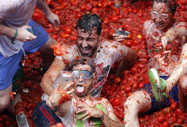 Revelers take pictures as they enjoy throwing tomatoes at each other, during the annual “Tomatina”, tomato fight fiesta, in the village of Bunol, 50 kilometers outside Valencia, Spain, Wednesday, August 30, 2017. At the annual “Tomatina” battle, that has become a major tourist attraction, trucks dumped 160 tons of tomatoes for some 20,000 participants, many from abroad, to throw during the hour- long Wednesday morning festivities. (Photo by Alberto Saiz/AP Photo) 