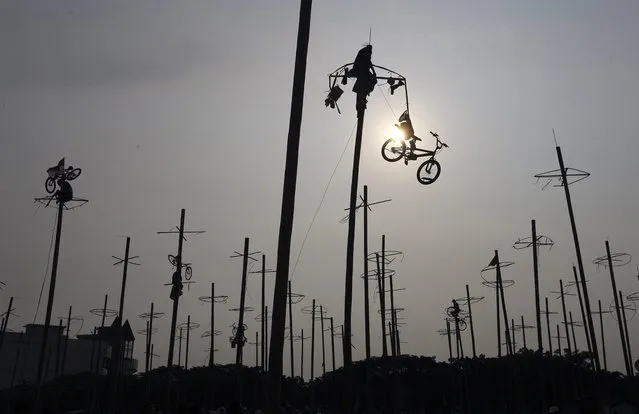 A participant pulls down a bicycle from the top of a greased pole during the “Panjat Pinang” event organised in celebration of Indonesia's 69th Independence Day at Ancol Dreamland Park in Jakarta August 17, 2014. (Photo by Reuters/Beawiharta)