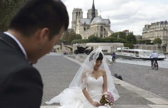 A Chinese couple gets ready for a pre-wedding photoshoot in front of the Notre-Dame Cathedral in Paris, France, August 28, 2015. (Photo by Philippe Wojazer/Reuters)