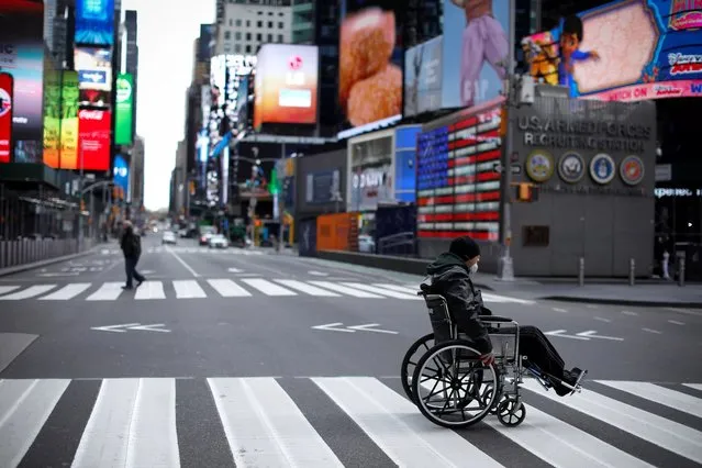 A man in a wheelchair crosses a nearly empty 7th Avenue in Times Square in Manhattan during the outbreak of the coronavirus disease (COVID-19) in New York City, New York, U.S., April 7, 2020. (Photo by Mike Segar/Reuters)