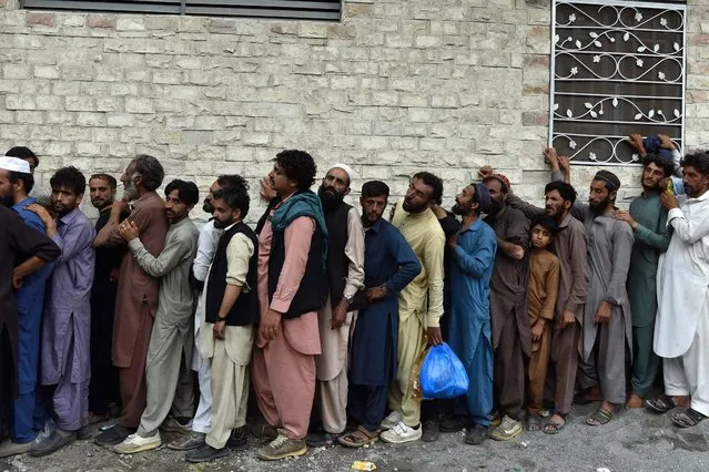 Flood-affected people stand in a queue as they wait to receive food packets at Bahrain town of Swat valley in Khyber Pakhtunkhwa province on August 31, 2022. Army helicopters flew sorties over cut-off areas in Pakistan's mountainous north on August 31 and rescue parties fanned out across waterlogged plains in the south as misery mounted for millions trapped by the worst floods in the country's history. (Photo by Abdul Majeed/AFP Photo)