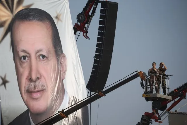 Turkish special forces unit stand on a crane as a giant portrait of Turkish President Recep Tayyip Erdogan is hanged over a Democracy and Martyrs' Rally in Istanbul, Sunday, August 7, 2016. A massive crowd of flag-waving supporters gathered in Istanbul Sunday for a giant rally to mark the end of nightly demonstrations since Turkey's July 15 abortive coup that left more than 270 people dead. (Photo by Emrah Gurel/AP Photo)