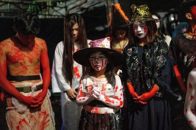 Children in Halloween costumes pray before they open the horror house in Manila, Philippines on October 31, 2022. (Photo by Lisa Marie David/Reuters)