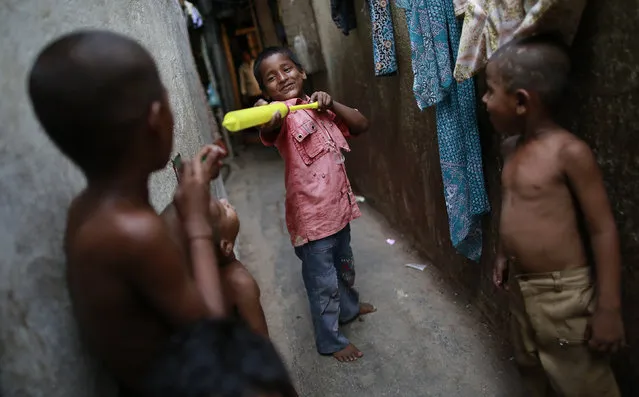 A boy scares other children with a watergun as they play in an alley in Dharavi, one of Asia's largest slums, in Mumbai May 28, 2014. (Photo by Danish Siddiqui/Reuters)