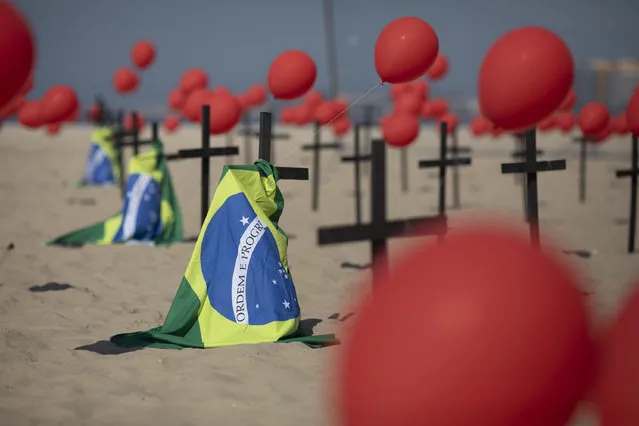 Crosses, red balloons and Brazilian nation flags are placed in the sand on Copacabana beach in a demonstration organized by Rio de Paz to honor the victims of COVID-19, as the country heads to a milestone of 100,000 new coronavirus related deaths, in Rio de Janeiro, Brazil, Saturday, August 8, 2020. (Photo by Mario Lobao/AP Photo)