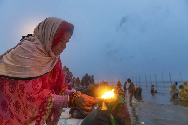 A Hindu devotee lights an oil lamp and offers prayers after taking ritualistic dips at “Sangam”, the meeting point of Indian holy rivers the Ganges and the Yamuna, on the auspicious day of “Paush Purnima” during the annual traditional fair of Magh Mela in Allahabad, India, Tuesday, January 2, 2018. Hundreds of thousands of devout Hindus are expected to take holy dips at the confluence during the astronomically auspicious period of over 45 days celebrated as Magh Mela. (Photo by Rajesh Kumar Singh/AP Photo)