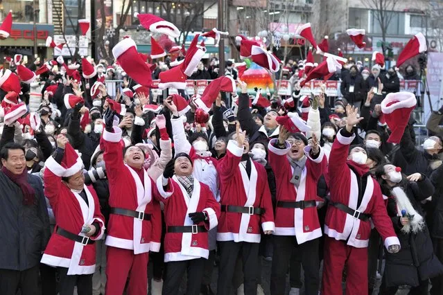 South Korean Prime Minister Han Duck-soo, fourth from right, and volunteers clad in Santa Claus costumes throw their hats in the air during a Christmas charity event before they deliver gifts for the underprivileged in Seoul, South Korea, Saturday, December 24, 2022. (Photo by Lee Jin-man/AP Photo)