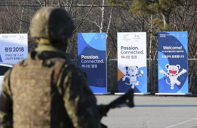 Posters showing the 2018 Pyeongchang Winter Olympic mascot are displayed as a South Korean army soldier stands guard at the Unification Observation post in Goseong, near the border with North Korea, South Korea, Friday, January 19, 2018. The rival Koreas agreed Wednesday to form their first unified Olympic team and have their athletes parade together for the first time in 11 years during the opening ceremony of next month's Winter Olympics in South Korea, officials said. (Photo by Ahn Young-joon/AP Photo)