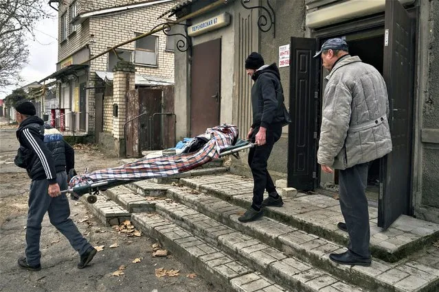 Local residents carry the body of a 20-year-old man killed in Russian shelling in Kherson, Ukraine, Thursday, January 5, 2023. (Photo by Alexei Alexandrov/AP Photo)