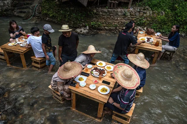 Customers eat lunch at a restaurant with tables in a stream of a river in Kampung Kemensah on the outskirts of Kuala Lumpur on July 14, 2020. (Photo by Mohd Rasfan/AFP Photo)