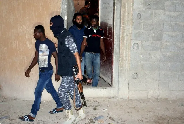 An officer of a Libyan anti-illegal immigrants unit conducts an early morning raid on migrants at a hideout in Tripoli, Libya, October 13, 2015. Libyan security forces charged with curbing illegal migration raided a hide-out for illegal migrants in Tripoli on Tuesday. (Photo by Hani Amara/Reuters)