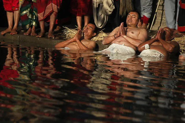 Nepalese Hindu devotees offer prayers while dipping half of their bodies into the Hanumante river during Madhav Narayan Festival in Bhaktapur, Nepal, Tuesday, January 2, 2018. During the festival devotees recite holy scriptures dedicated to the Hindu goddess Swasthani and Lord Shiva. Unmarried women pray to find a good husband while those married pray for the longevity of their husbands by observing a month-long fast. (Photo by Niranjan Shrestha/AP Photo)