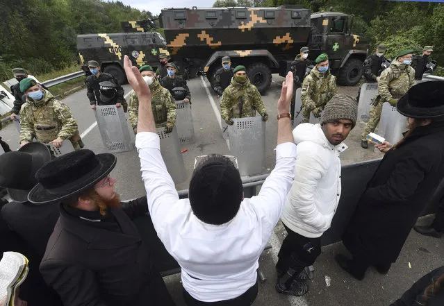 Hasidic Jewish pilgrims gather in front of Ukrainian border guards at the checkpoint Novaya Guta near Novaya Guta, Belarus, Friday, September 18, 2020. Ukrainian officials say that thousands of Hasidic Jewish pilgrims stuck on the Ukrainian border due to coronavirus restrictions have started turning back. About 2,000 ultra-Orthodox Jewish pilgrims traveled to Belarus's border with Ukraine in hope of traveling to the Ukrainian city of Uman to visit the grave of an important Hasidic rabbi who died in 1810, Nachman of Breslov. (Photo by AP Photo/Stringer)