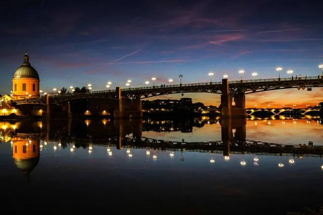 This photograph taken at dusk on October 3, 2022, shows the Saint-Pierre bridge on the Garonne river and the landmark Dome de La Grave (L) in Toulouse, southern France. (Photo by Charly Triballeau/AFP Photo)