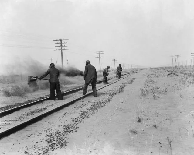 Keeping the rails clear so trains could go through was one of the major tasks of rail road men in western Kansas during the dust storms. Here is a group sweeping the dust from the tracks, April, 13, 1935, Syracuse, Ks. (Photo by AP Photo)