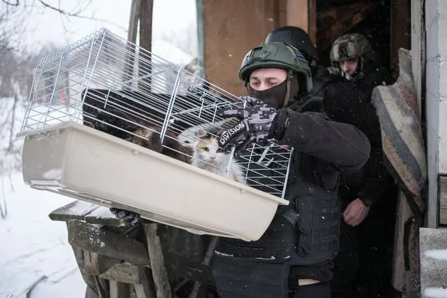 A volunteer carries the cats of Lidiia Chynyakova, 89, during her evacuation from her home, amid Russia's attack on Ukraine, in Chasiv Yar, Donetsk region, Ukraine on February 12, 2023. (Photo by Marko Djurica/Reuters)