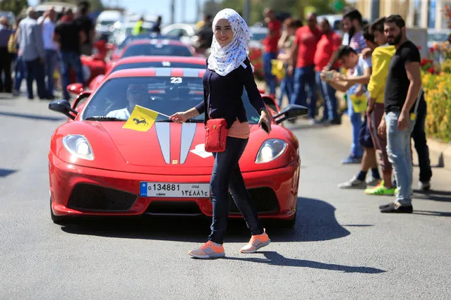 A woman walks near a Ferrari car during a Ferrari ride around Lebanon, in the town of Marjayoun, South Lebanon October 1, 2016. (Photo by Ali Hashisho/Reuters)