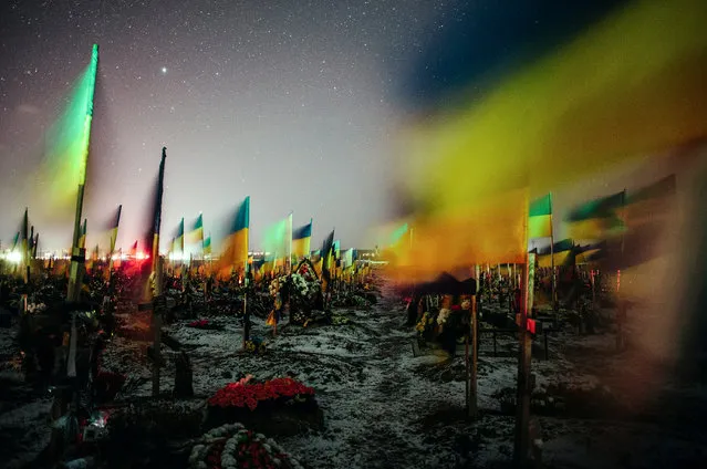 An image taken with a slow shutter speed of Ukrainian national flags waving over the graves of fallen Ukrainian soldiers in a military cemetery in Kharkiv, northeastern Ukraine, late 22 February 2023 (issued 23 February 2023), nearly one year since the start of the Russian invasion. Russian troops entered Ukrainian territory on 24 February 2022, starting a conflict that has provoked destruction and a humanitarian crisis. One year on, fighting continues in many parts of the country. (Photo by Pavlo Pakhomenko/EPA/EFE)