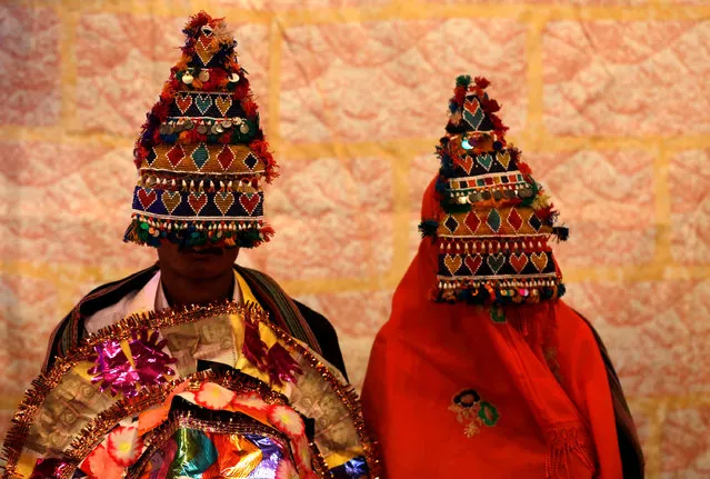 A bride and groom wearing traditional handmade garlands wait for their wedding to start during a mass marriage ceremony in Karachi, Pakistan, January 24, 2016. (Photo by Akhtar Soomro/Reuters)