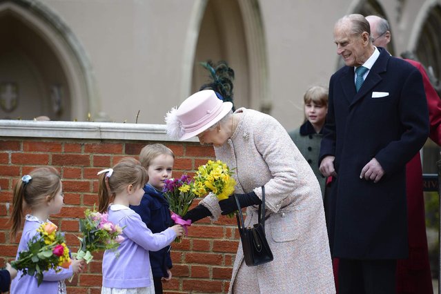 Britain's Queen Elizabeth collects flowers from children as she leaves The Deanery at St Georges Chapel with Prince Philip (R) at Windsor Castle after the Easter service in Windsor, southern England, March 31, 2013.  (Photo by Paul Hackett/Reuters)